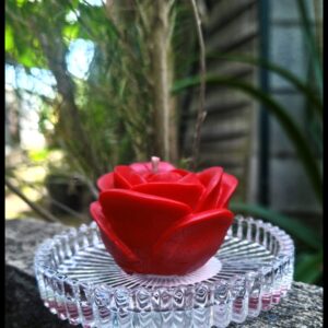 Bougie moulée parfumée en forme de rose sur sa coupelle en verre